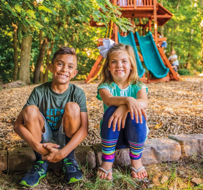 become a Woodplay dealer - kids sitting in front of a backyard playset