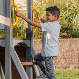 boy playing on jack and june haven II playset holding on to safety handles.