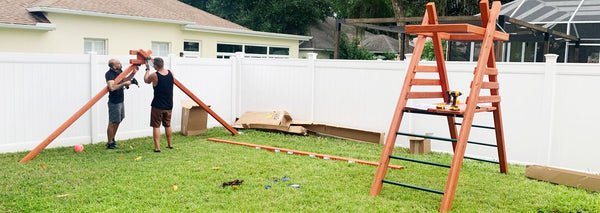 people installing backyard wooden swing set