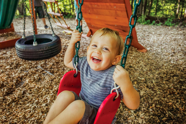 little boy smiling on a red swing
