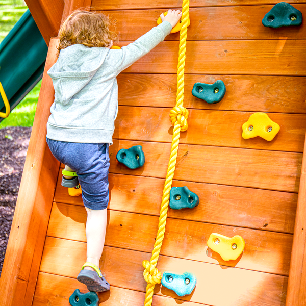 child climbing rock wall on wooden playset