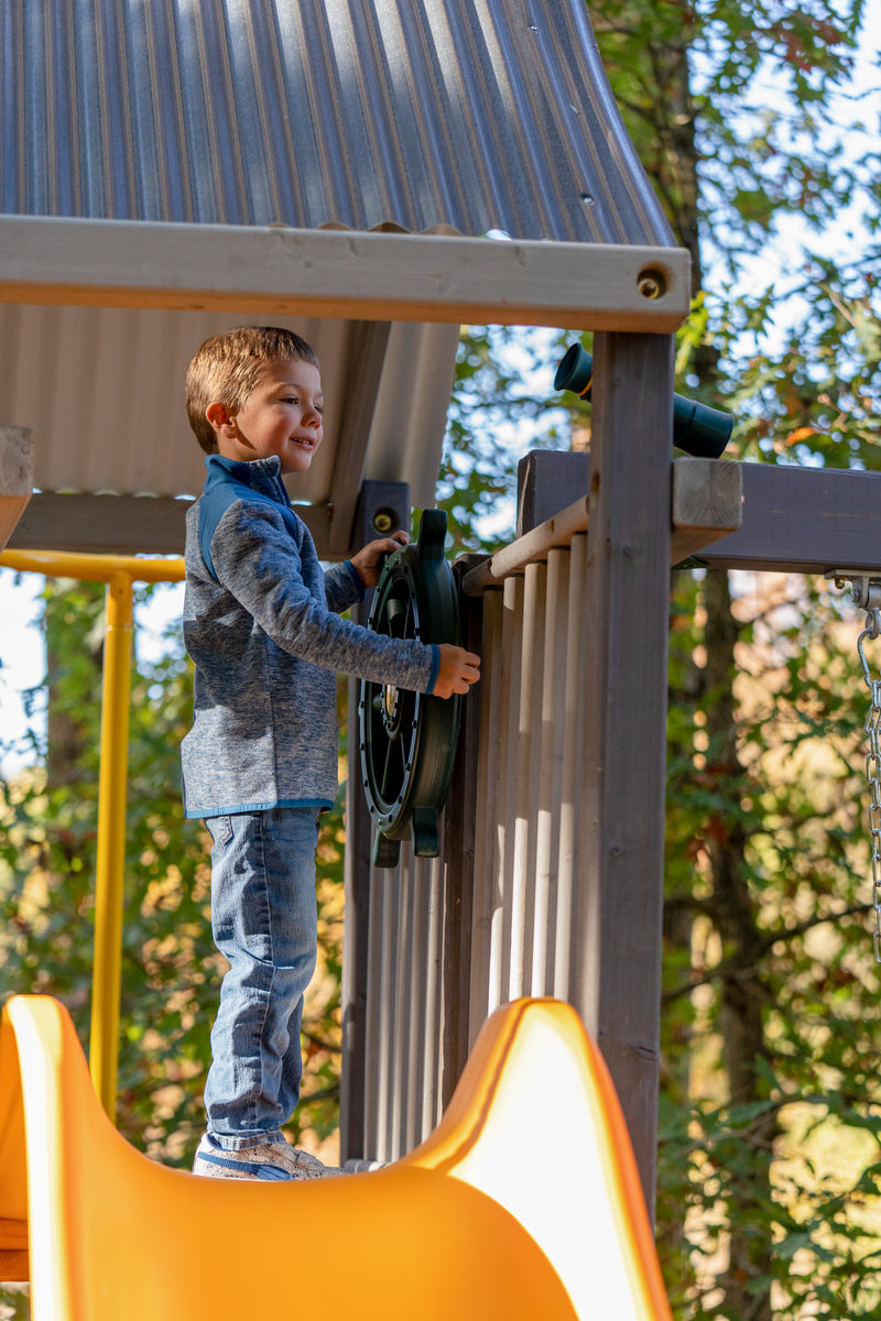 child playing on swingset and steering ship's wheel