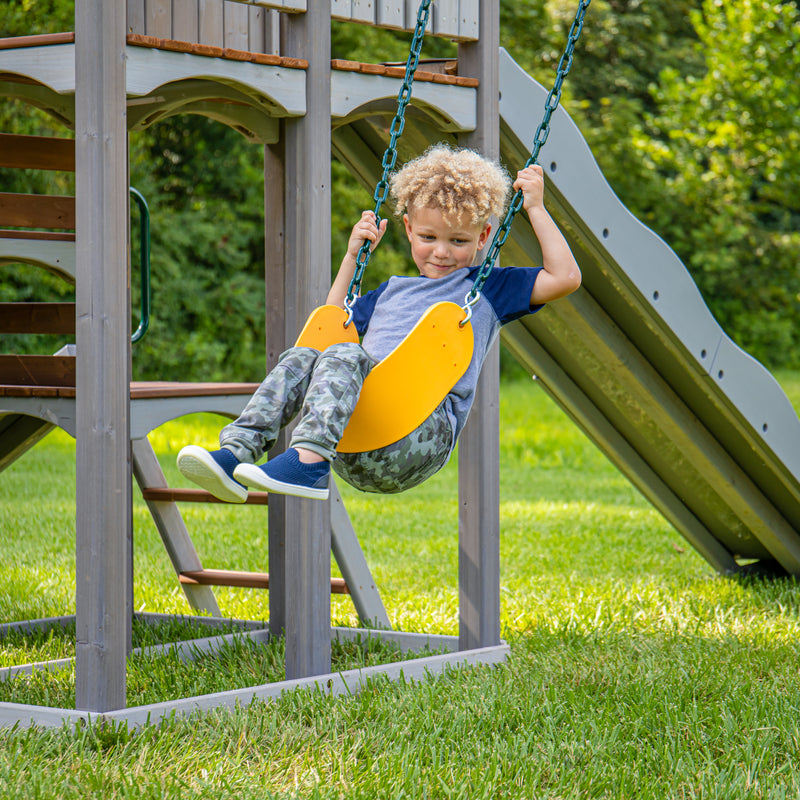 Little boy swinging on belt swing on jack and june haven outdoor swing and slide set